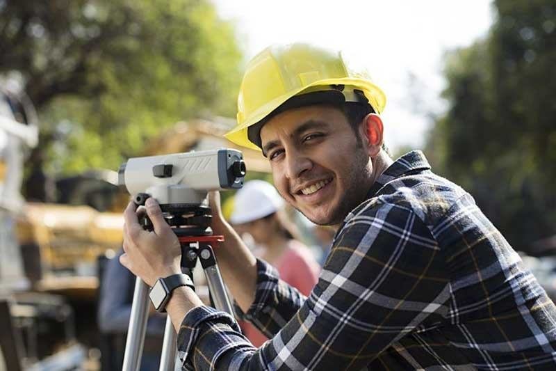 Trainee in a hard hat using surveying equipment